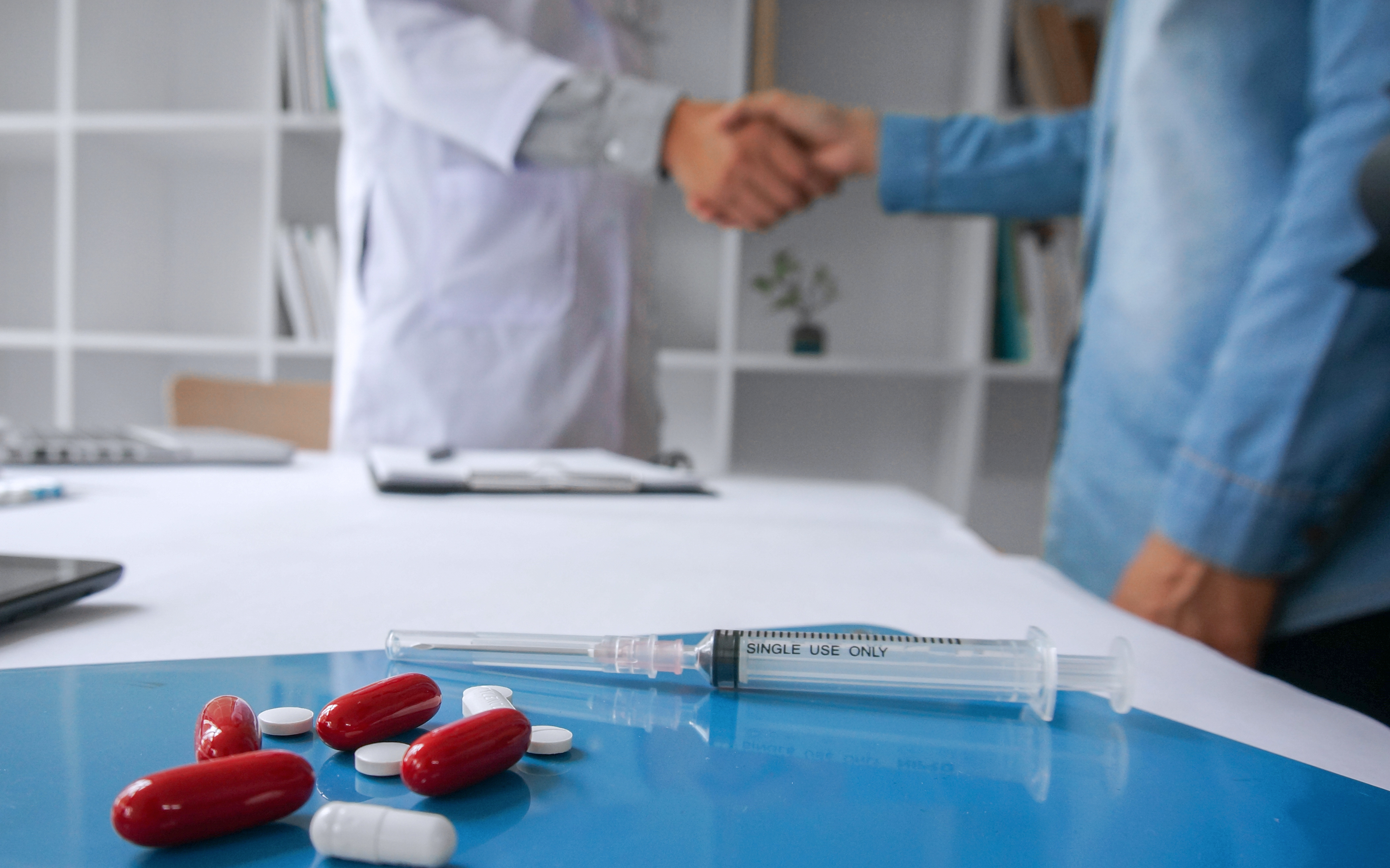 Medic shaking hands with salesman with drugs and syringe