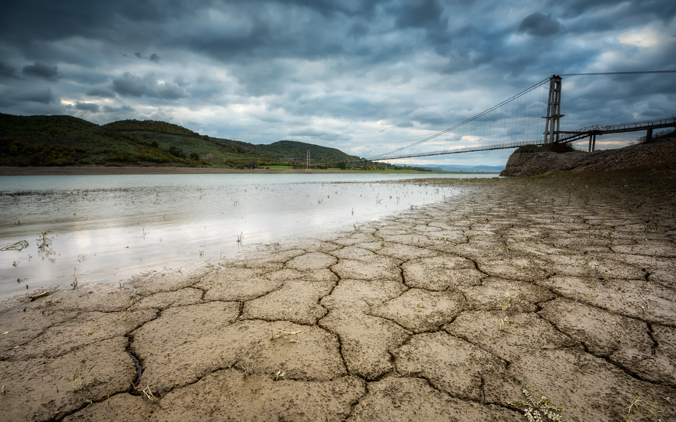 dried up river bed and gloomy clouds over a bridge